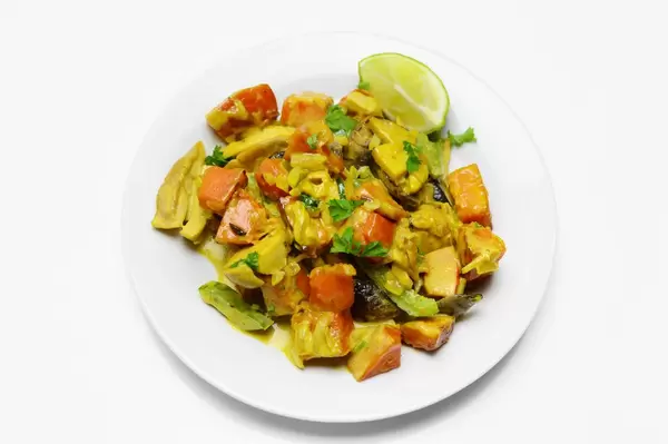 Gerösteter Kürbis mit Pilzen, dekoriert mit Petersilie und Zitronenschnitz auf weißem Teller