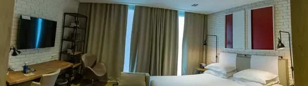 Gesamtansicht des Hotelzimmers für zwei Personen im "The Corner Hotel Barcelona", Spanien, mit geschlossenen Vorhängen und weißem Mauerstein