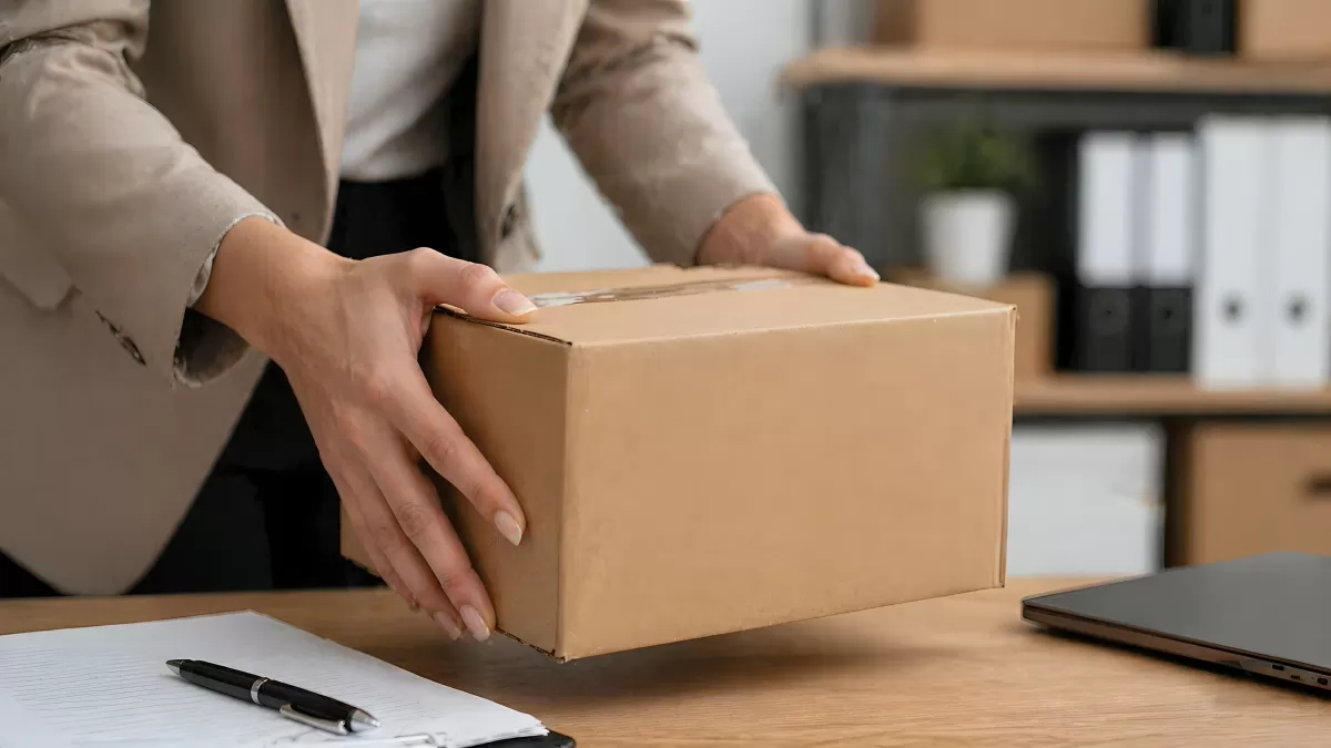 Geschäftsfrau hält Paket im Büro über Schreibtisch