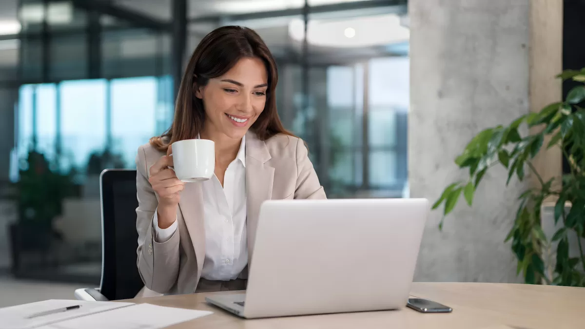 Geschäftsfrau mit Kaffee arbeitet am Laptop im Büro