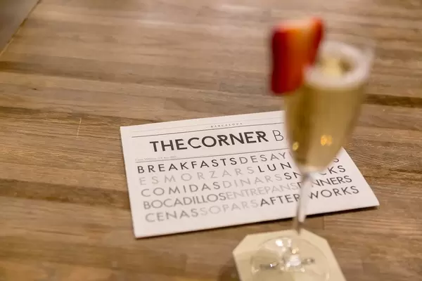 Geschäftskarte des Restaurants & Bar im The Corner Hotel, neben unscharfen Sekt-Drink mit Erdbeerstück, in Barcelona, Spanien