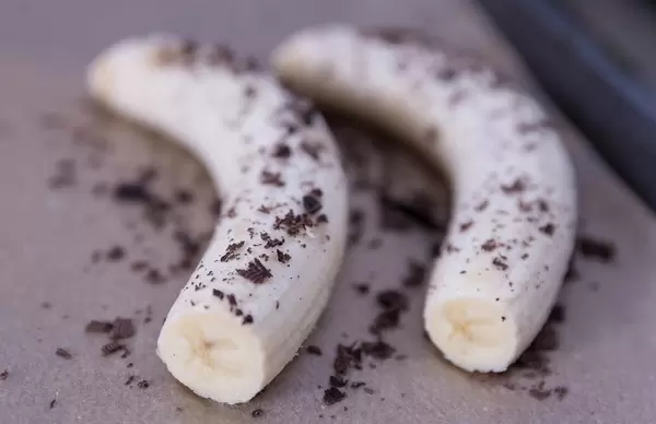 Geschälte Bananen mit Schokoladenraspeln vor dem Backen