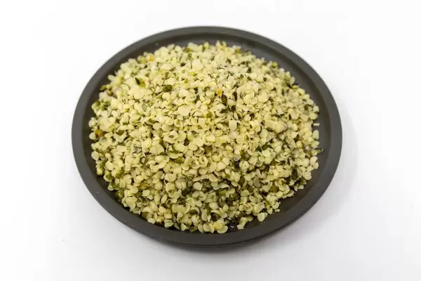 Geschälte Bio-Hanfsamen auf einem schwarzen Teller