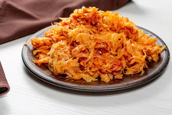 Geschmortes Kraut auf braunem Teller und weißem Holztisch