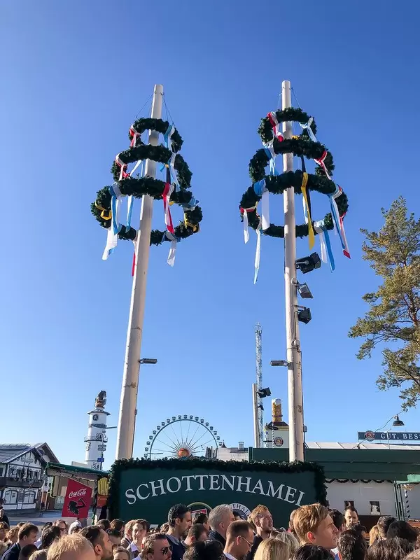 Geschmückte Maibäume auf dem Oktoberfest am Schottenhamel Festzelt und die wartenden Besucher