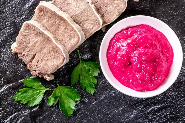 Geschnittene gekochte Zunge mit Petersilienblättern und Meerrettichsauce