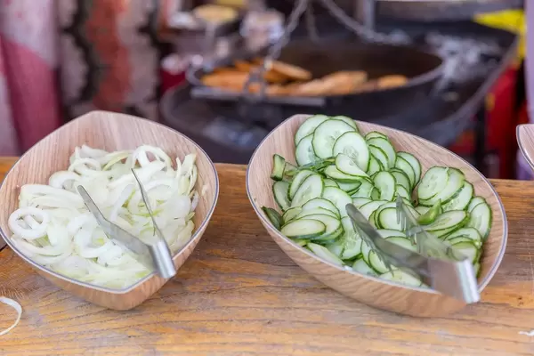 Geschnittene Gurken und Zwiebeln in Schüsseln