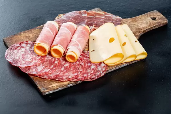 Geschnittene Salami, Schinken und Käse auf einem alten Holzschneidebrett