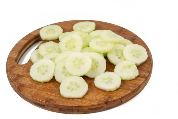 Geschnittene Salatgurke auf einem runden Holzbrettchen