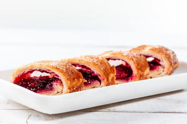 Geschnittene Stücke eines Kirschstrudels auf einem weißen Teller