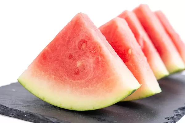 Geschnittene Wassermelone, aufgereiht auf einem schwarzen Schiefersteinbrettchen