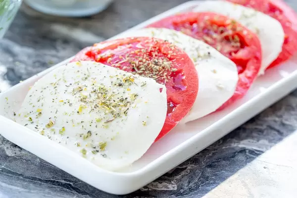 Geschnittener Mozzarella-Käse und Tomaten mit getrockneten italienischen Kräutern auf einem Teller
