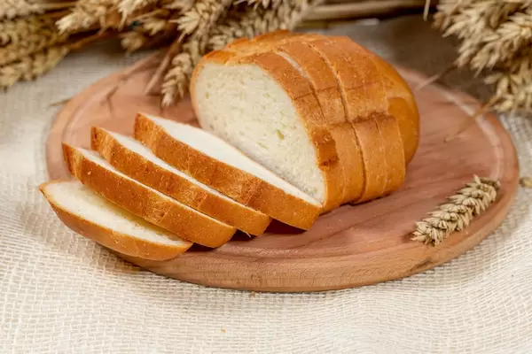 Geschnittenes Weißbrot auf einem Brettchen mit Weizenähren