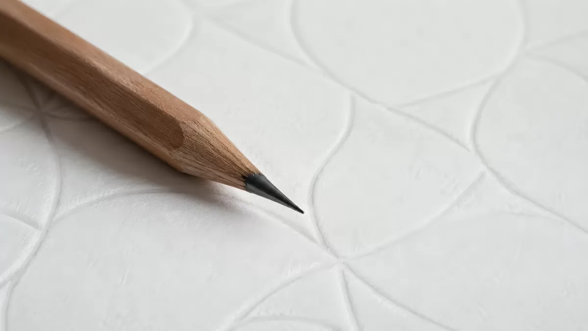 Gespitzter Bleistift liegt auf strukturiertem Papier