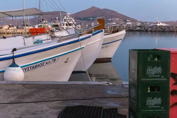 Gestapelte Bierkisten am Hafen, mit Schiffen auf dem Mittelmeer vor der Insel Paros, Griechenland