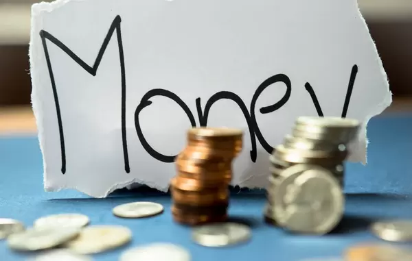 Gestapelte Münzen mit der Schrift Money im Hintergrund