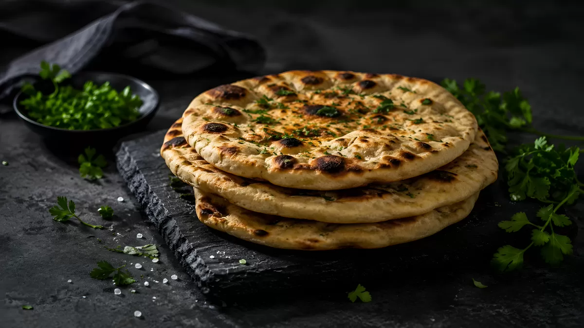 Gestapelte Naan-Brote mit Kräutern auf Schieferplatte