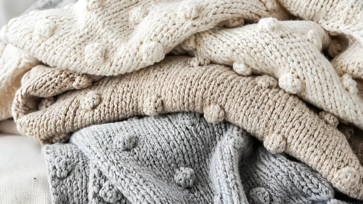Gestapelte Strickdecken in Grau, Beige und Weiß