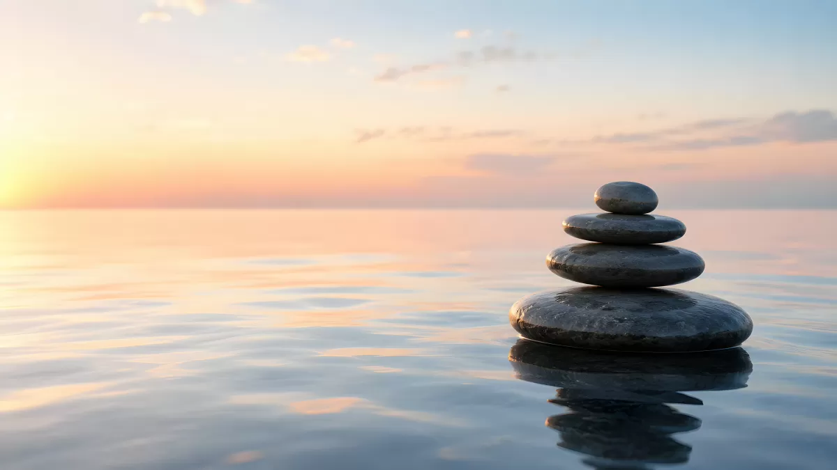 Gestapelte Zen-Steine im ruhigen Wasser bei Sonnenuntergang