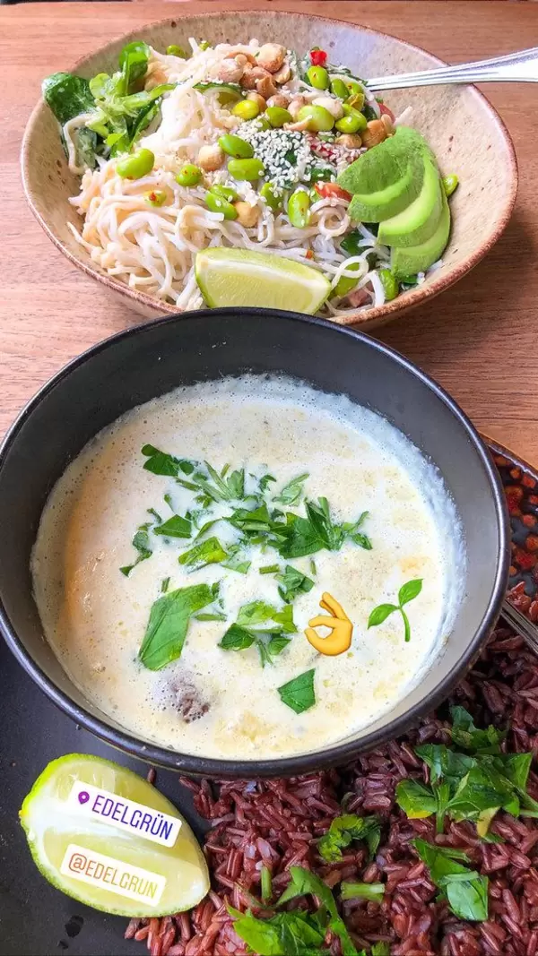 Gesund essen bei Edelgrün in Köln-Ehrenfeld: Teller mit Reisnudeln, Avocado, Edamame, Paprika, und Schüssel mit grünem Curry (scharf) serviert auf Vollkornreis