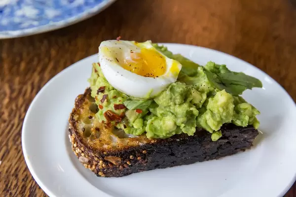 Gesund frühstücken in Chicago mit Ei und Avocado auf Mehrkornbrot-Toast, Nahaufnahme auf einem kleinen weißen Teller