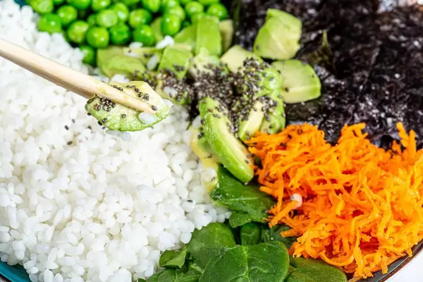Gesunde, ausgewogene Ernährung: Nahaufnahme einer Avocadoscheibe auf Essstäbchen, mit Chiasamen