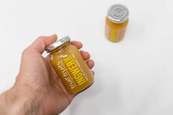 Gesunde Energy-Boosters: Mann hält ein Ingwer Shot von true fruits in der Hand
