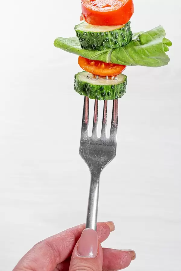 Gesunde Ernährung: Frau hält eine Gabel mit frischem Gemüse