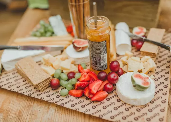 Gesunde Frühstücksplatte mit Käsestücken, Beeren, Weintrauben und Kirschen, auf einem Holztisch