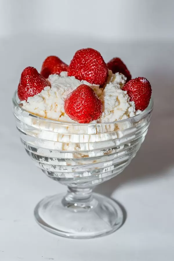 Gesundes Frühstück aus Hüttenkäse und frischen Erdbeeren in Glasschale