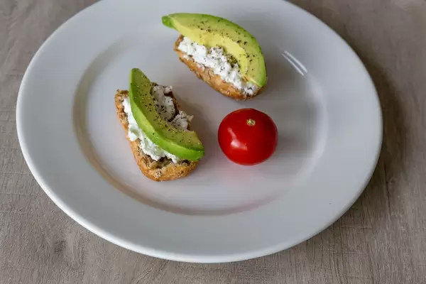 Gesundes, nahrhaftes Frühstück mit Vollkornbrot, Avocado, Hüttenkäse und Tomate
