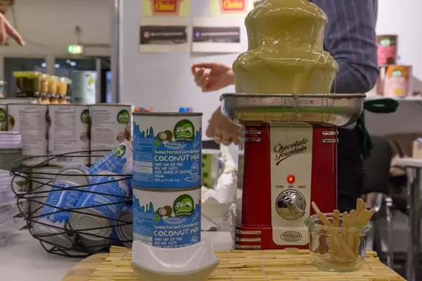 Gesüßte vegane Bio Kokosnuss-Kondensmilch aus der Dose wird in einem Schokoladenbrunnen präsentiert