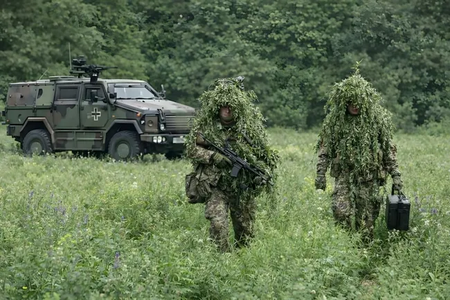 Getarnte Soldaten mit Gewehren und Militärfahrzeug in Naturlandschaft