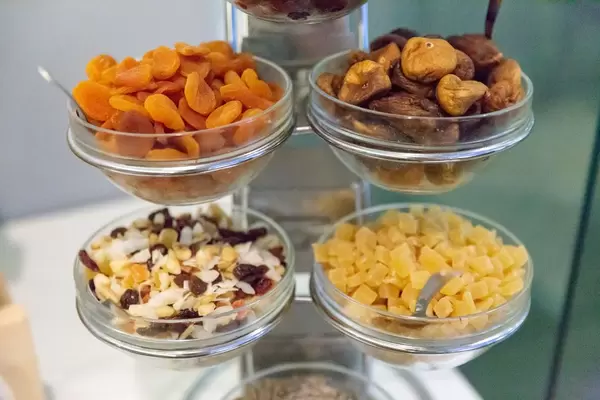 Getrocknete Früchte und Müsli an einem Buffet - Aprikosen, Feigen und kandierte Ananasstückchen in Schälchen