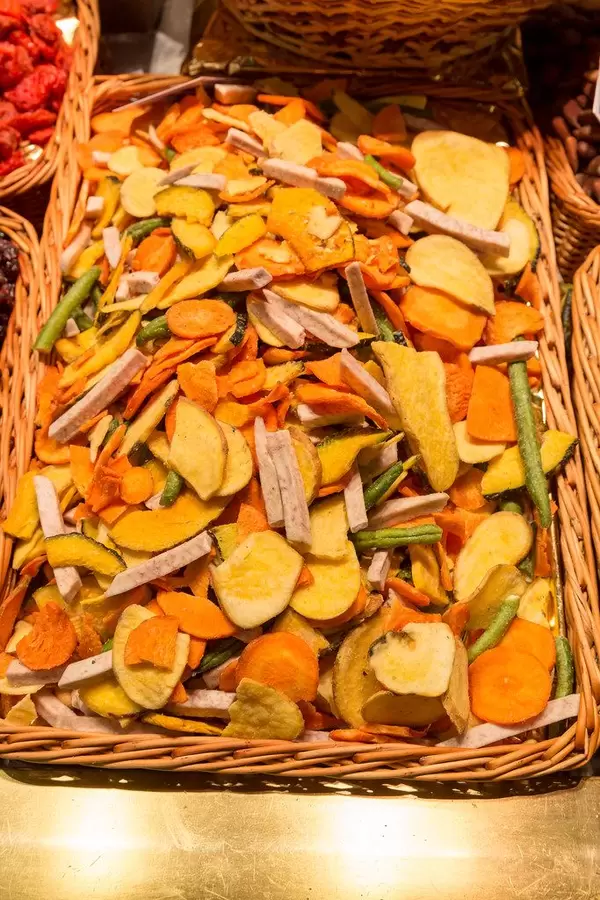 Getrocknete Gemüsechips in einem Bastkorb am Lebensmittelstand in der bekanntesten Markthalle Barcelonas "Mercat de la Boqueria" in Spanien