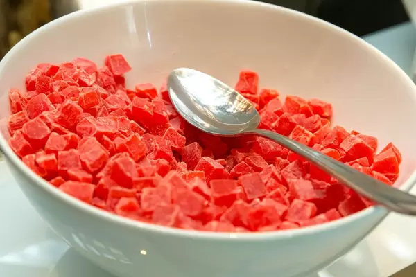 Getrocknete Papaya-Würfel mit Löffel in weißer Schale