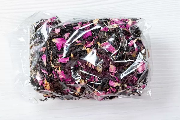 Getrockneter Krim Schwarztee mit rosa Blütenblättern in transparenter Verpackung