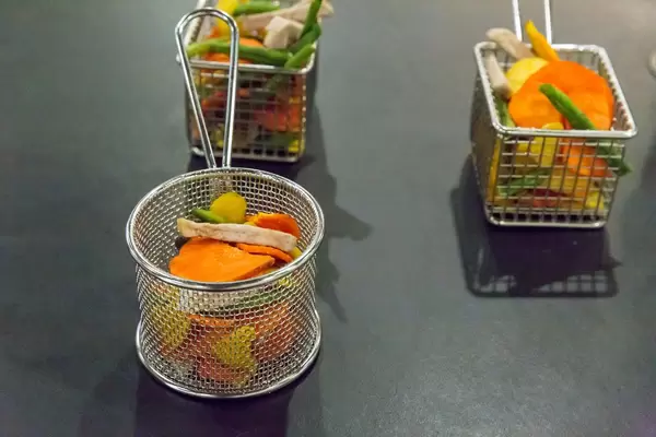 Getrocknetes Gemüse in Friteusenkörben vor schwarzem Hintergrund