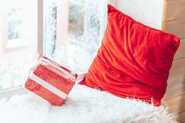 Gift and red pillow on the windowsill in winter