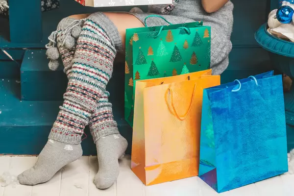 Gift bags near the legs of a girl sitting on the steps