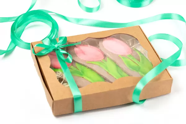 Gift box with gingerbread tulips and green ribbon on white