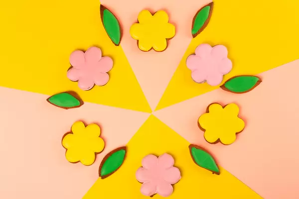 Gingerbread cookies - flowers with colored glaze on a pink and yellow background, top view