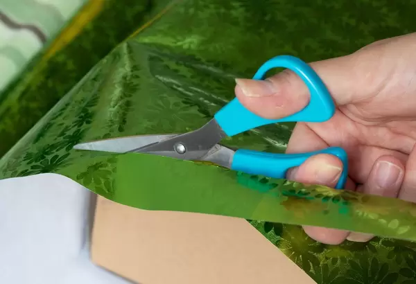 Girl cutting wrapping paper with scissors