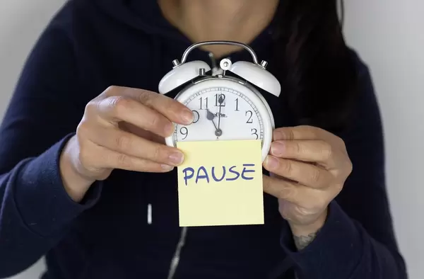 Girl holding a clock with pause note