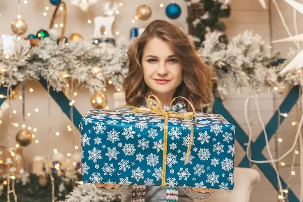 Girl holding a large blue gift box in front of her