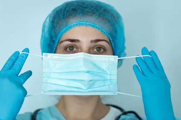 Girl in medical clothes and gloves with a mask in front of her face