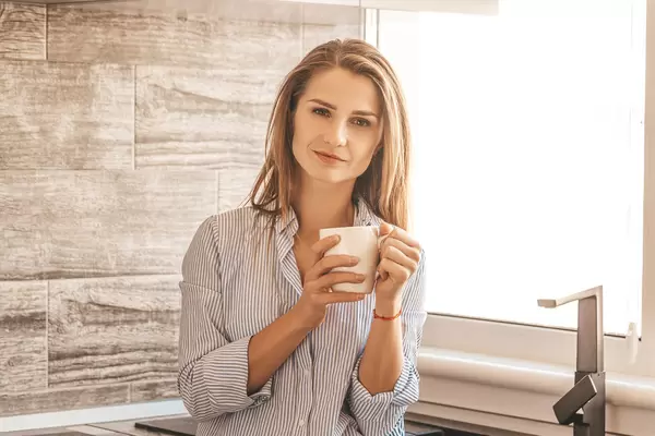 Girl in the kitchen stands with a cup of tea