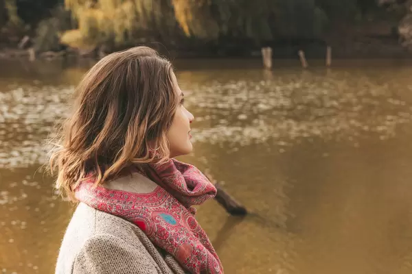 Girl looks at the lake, beautiful autumn landscape