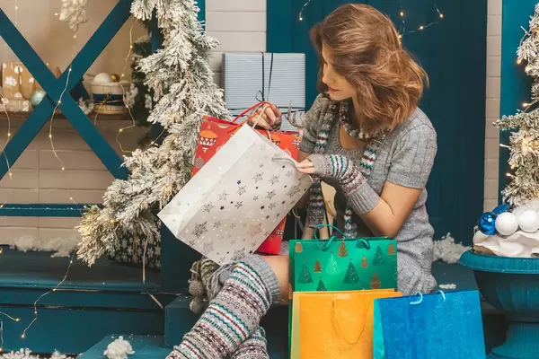 Girl peeks into a gift bag, the concept of gifts for the winter holidays