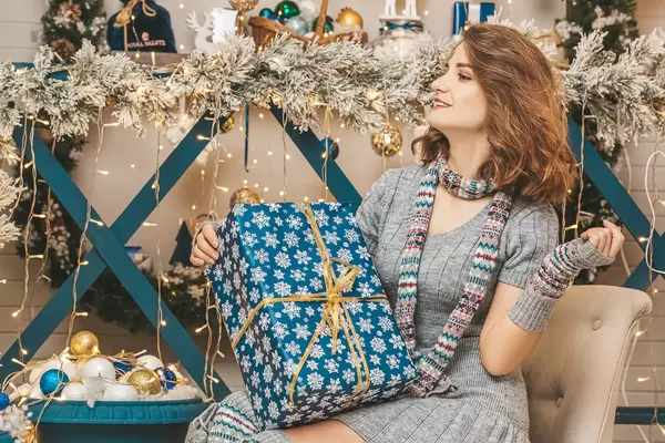 Girl sitting on an armchair in a christmas interior with a gift